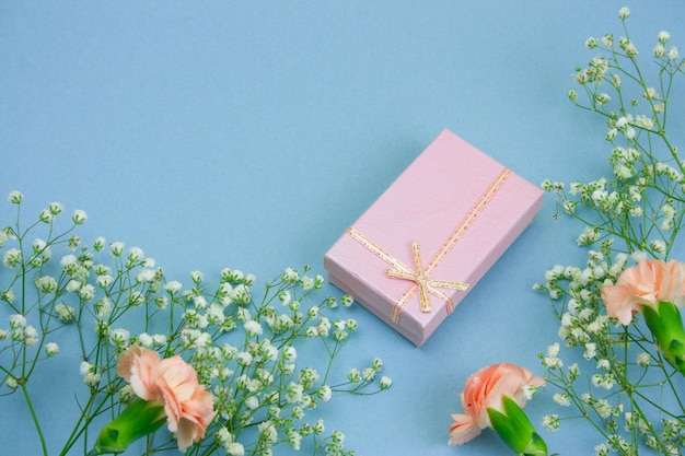 Geschenkdoos en bloemen op blauwe achtergrond