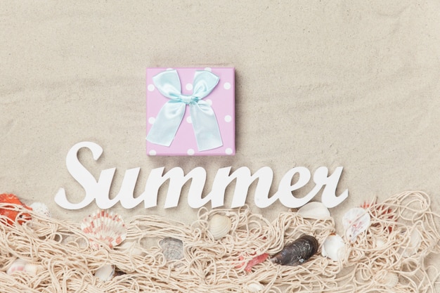 Geschenkdoos en woord zomer op zand achtergrond