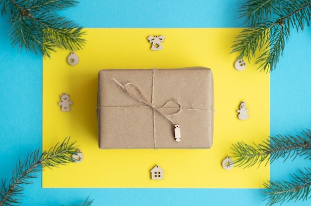 geschenkdoos in ambachtelijk papier gebonden met een tourniquet ligt op een gele kerstachtergrondM