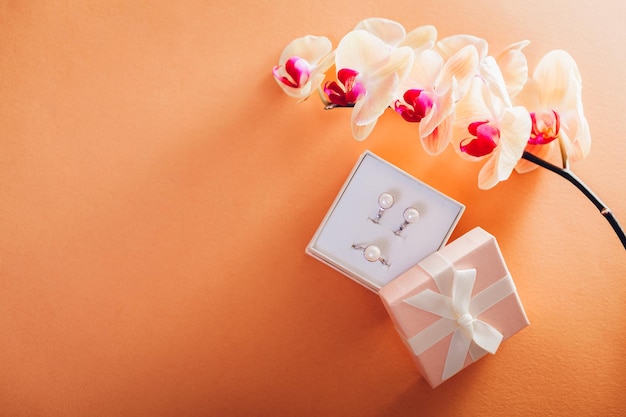 Geschenkdoos met een set van perl sieraden omringd met orchidee cadeau voor vrouwendag