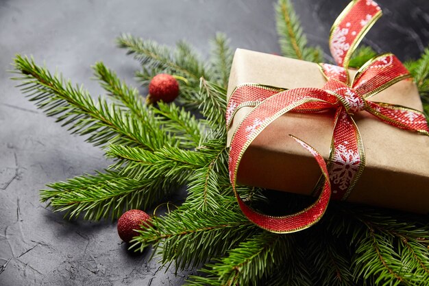 Geschenkdoos met groene kerstboomtak en rode ballen op zwarte achtergrond