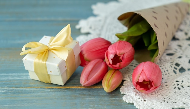 Geschenkdoos met lang roze lint en tulpen op houten achtergrond