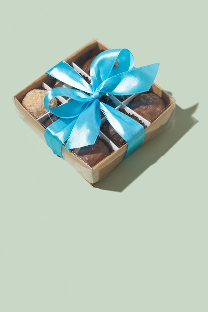 Geschenkdoos met strik met chocolade ambachtelijke snoepjes binnen op groene achtergrond