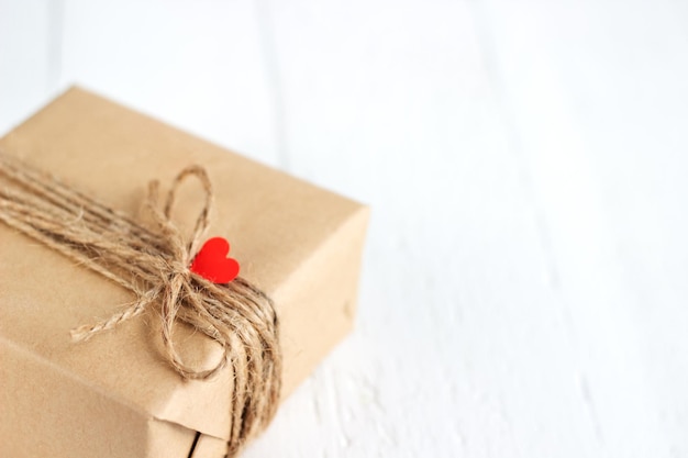 Geschenkdoos van ambachtelijk papier met hartjes op de witte houten achtergrond Valentine39s Day