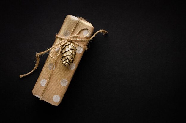 Geschenkdoos verpakt in ambachtelijk papier met gouden kegel op zwart
