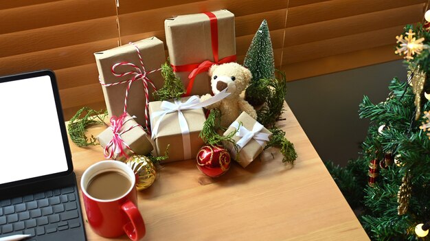 Geschenkdozen, computertablet en koffiekopje op houten tafel in de buurt van de kerstboom thuis.