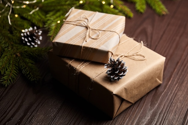 Geschenkdozen met kerstlicht en boomtak met kegels op bruine houten ondergrond