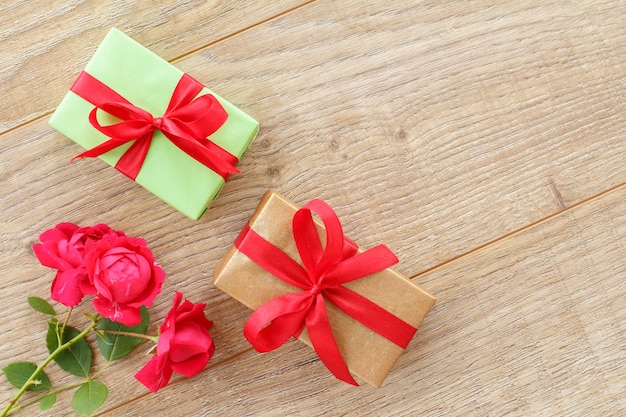 Geschenkdozen met rode linten en mooie roze bloemen op de houten achtergrond. Concept van het geven van cadeau op feestdagen. Bovenaanzicht.