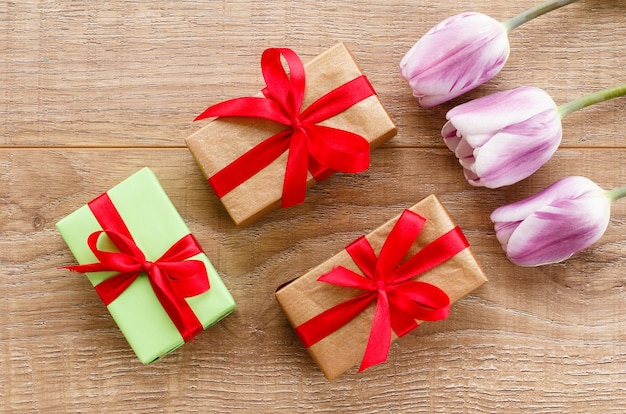 Geschenkdozen met rode linten en tulpen op houten planken