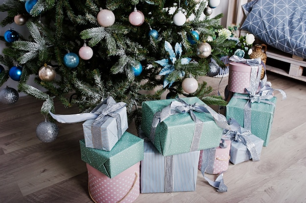 Geschenkdozen onder nieuwjaarsboom in witte kamer. Gelukkig wintervakantie concept.