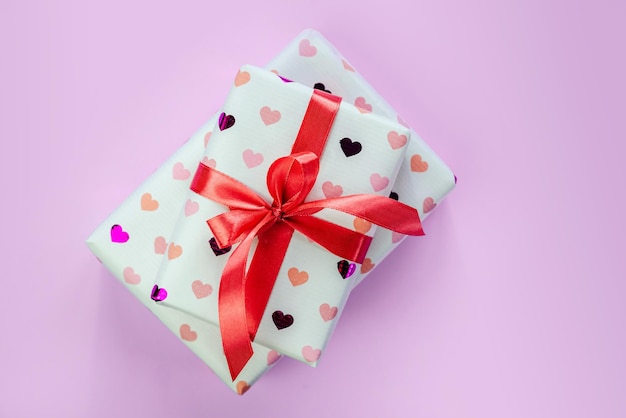 Geschenkdozen verpakt in hartpatroonpapier met rode strik op roze achtergrond