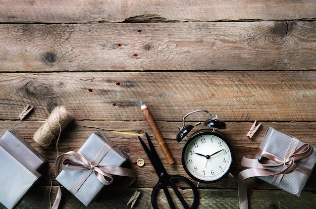 Geschenkdozen, zwarte wekker, pen, schaar op houten. Voorbereiding op verjaardag, Kerstmis, Nieuwjaar.