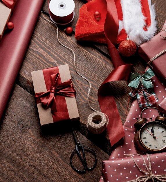 Geschenken en rood papier in de tijd van het inpakken op houten tafel