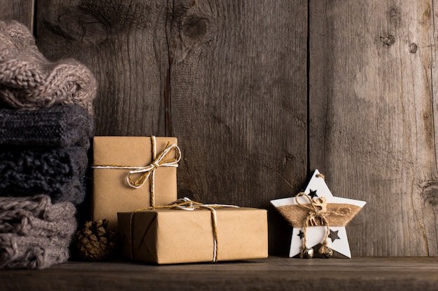 Geschenken in kraftpapier op een oude houten plank, naast gebreide sjaals.