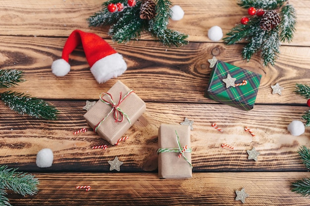 Geschenken, Kerstman hoed, Spar takken en bessen, op een houten textuur achtergrond. Uitzicht van boven. Handgemaakt.