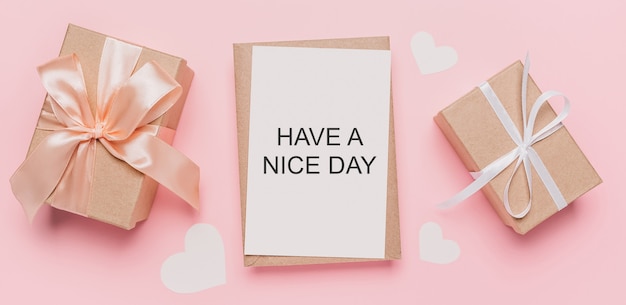 Geschenken met notitiebrief op geïsoleerde roze ruimte, liefde en valentijnskaartconcept met tekst have a nice day