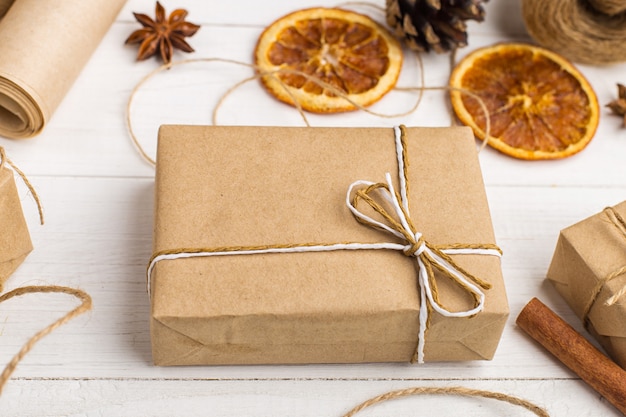 Geschenken van ambachtelijk papier, gedroogde sinaasappel, kaneel, dennenappels, anijs op een witte tafel