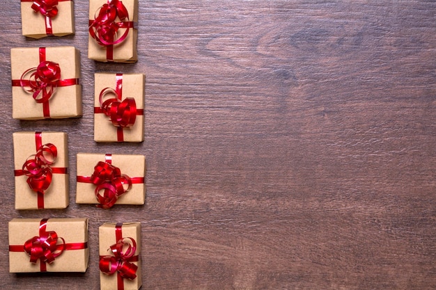 Geschenken verpakt in kraftpapier en rood lint en strik op een houten ondergrond