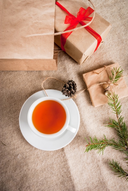 Geschenkverpakking en brieven, kaarten voor kerstgroet. enveloppen met brieven, geschenken, kerstboomtakken en dennenappels liggen op een houten tafel liggen, een kopje geurige hete thee, bovenaanzicht