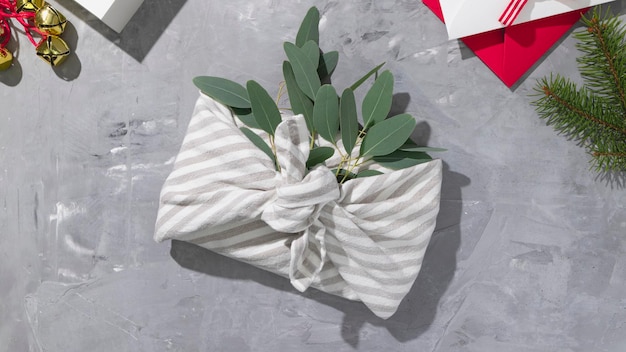 Geschenkverpakking volgens furoshiki zero waste-stijl met eucalyptus op een grijze achtergrond