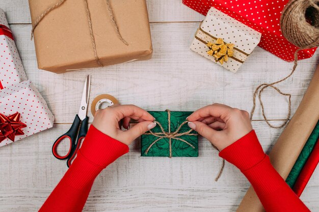 Geschenkverpakking. vrouw pakt vakantiegeschenken thuis op houten tafel.