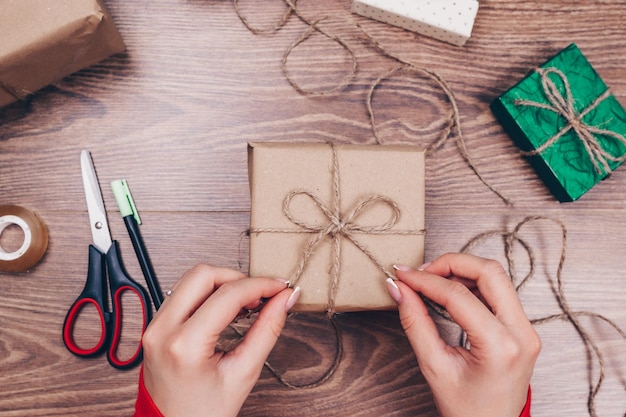 Geschenkverpakking. Vrouw pakt vakantiegeschenken thuis op houten tafel.