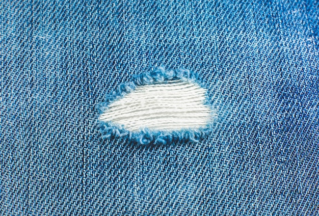 Gescheurd materiaal van blauwe hipsterjeans. Vernietigde denim doek textuur. Detailopname.