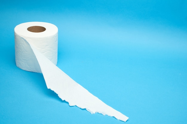 Gescheurde witte wc-papierrol op minimalistische blauwe achtergrond