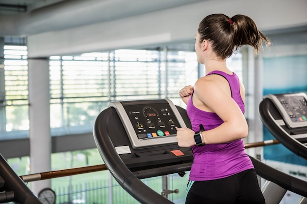 Geschikt brunette die op tredmolen in de gymnastiek lopen