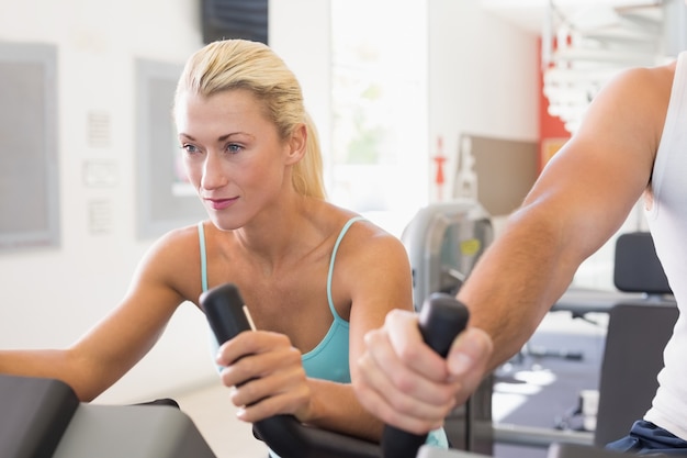 Foto geschikt jong paar dat aan hometrainers bij gymnastiek werkt