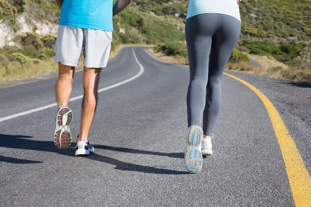 Geschikt paar die samen onderaan een weg op een zonnige dag lopen