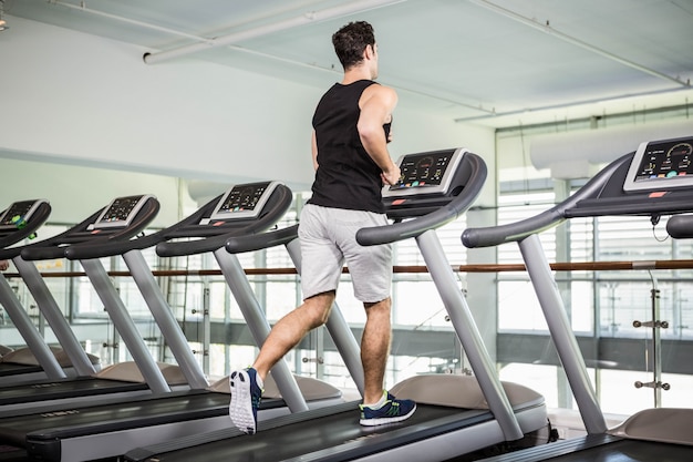 Geschikte mens die op tredmolen bij de gymnastiek lopen