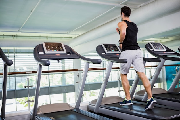 Geschikte mens die op tredmolen bij de gymnastiek lopen