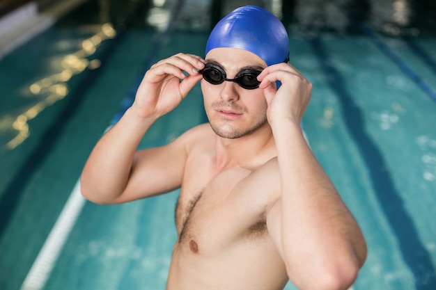 Geschikte mens die zijn beschermende brillen bij de pool aanpast