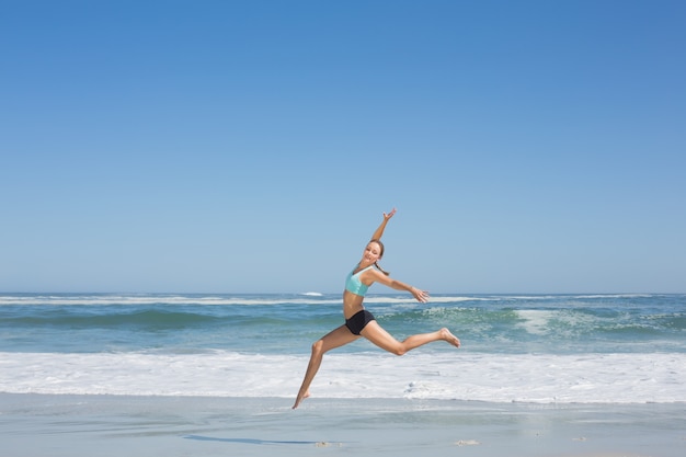 Geschikte vrouw die elegant op het strand springt