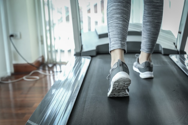 Foto geschiktheidszaal met mensen die op tredmolen naast venster met exerci van de daglichtochtend lopen