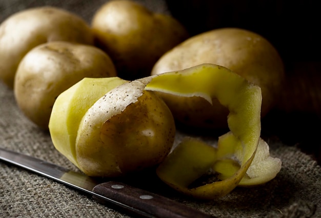 Geschilde aardappelen met een mes op tafel Foto in een donkere sleutel