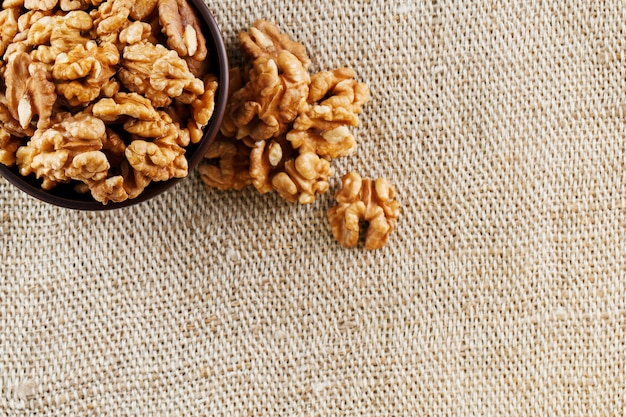 Geschilde walnoten in een houten, donkerbruine kop op een jute doek