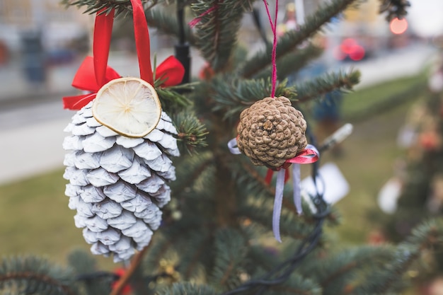 Geschilderde dennenappel en gedroogde citroen op kerstboom Diy decoratie Selectieve focus