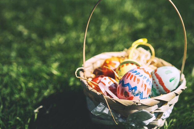 Geschilderde paaseieren in rieten mand Kinderen verzamelen kleurrijke eieren buitenshuis Feestelijk familie traditioneel speelspel op Pasen-achtergrond met kopieerruimte