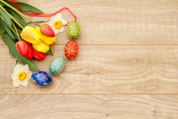 Geschilderde paaseieren, tulpen en narcissen op houten planken Bovenaanzicht