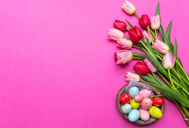Geschilderde paaseierenpastelkleuren en de roze achtergrond van het tulpenboeket
