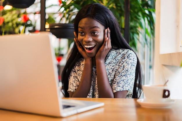 Geschokt Afrikaanse vrouwelijke freelancer staart op laptopcomputer met afgeluisterde ogen