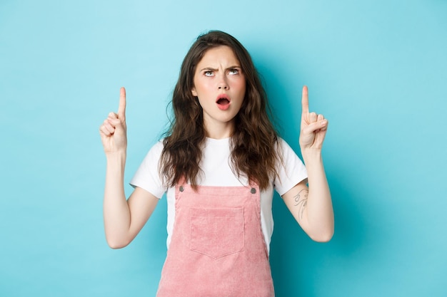 Geschokt beledigde jonge vrouw fronsend naar adem snakkend en kijkend met een teleurgesteld en beledigd gezicht showin