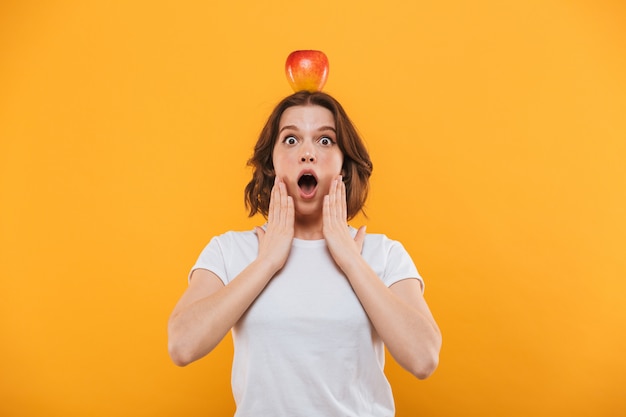 Geschokt jonge vrouw met appel op zoek camera.