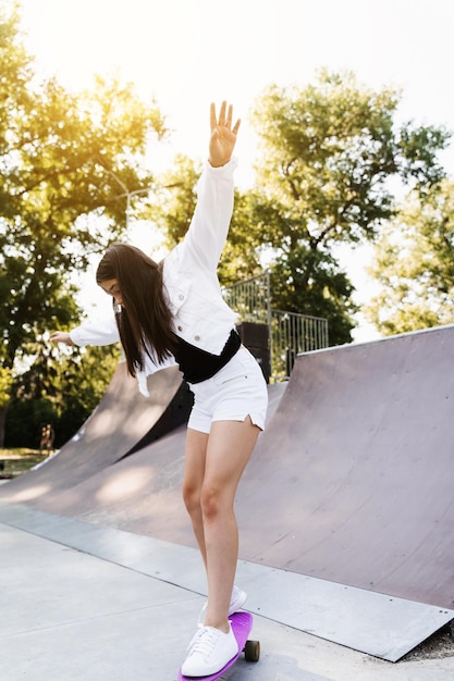 Geschokt kindmeisje voor val van pennyboard op skateparkspeeltuin bij zonsondergang Sportuitrusting voor kinderen Actieve tiener met pennyboard op skateparkspeeltuin