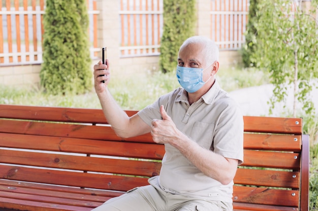 Geschokt man met medische gezichtsmasker met behulp van de telefoon naar nieuws te zoeken en tumb opdagen