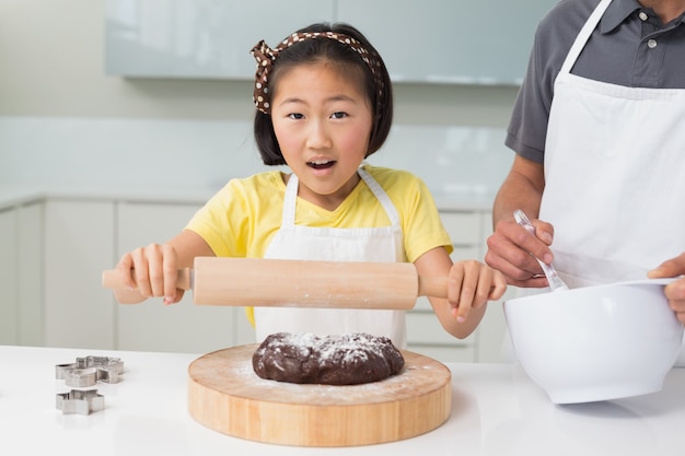 Geschokt meisje met haar vader die koekjes in keuken voorbereidt