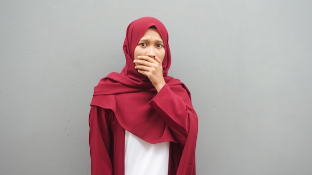 Geschokt verrast Aziatische moslimdame die naar de camera kijkt met grote ogen en open mond, wow verbijsterd gebaar