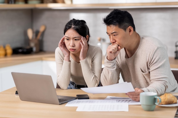 Geschokte Aziatische man en vrouw die hun uitgaven controleren